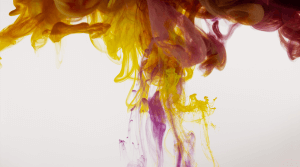 immagine di inchiostri a base d’acqua, di colore prevalentemente giallo, fucsia e nero, che si espandono, disperdono e si mescolano in quella che è una soluzione acquosa.